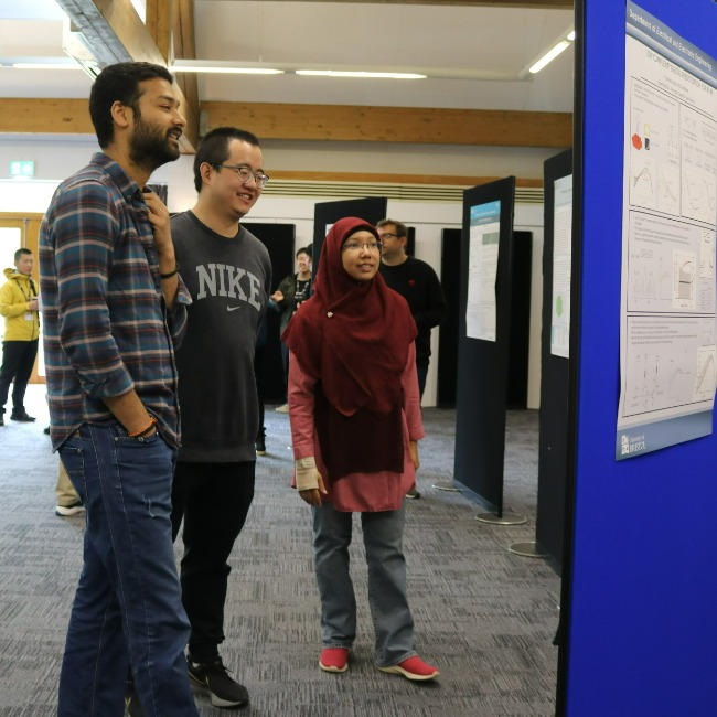 Postgraduate students discussing their research posters.
